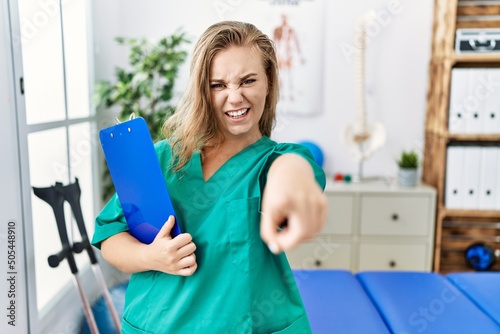 Young caucasian woman working at pain recovery clinic pointing displeased and frustrated to the camera  angry and furious with you