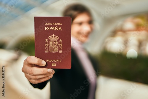 Young beautiful businesswoman smiling happy holding spainish passport at the city. photo