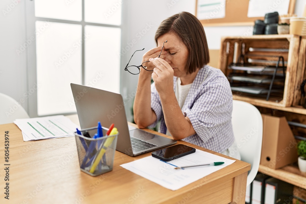 Middle age hispanic woman businesswoman working using laptop resting eyes at business office Middle age hispanic woman businesswoman working using laptop resting eyes at business office