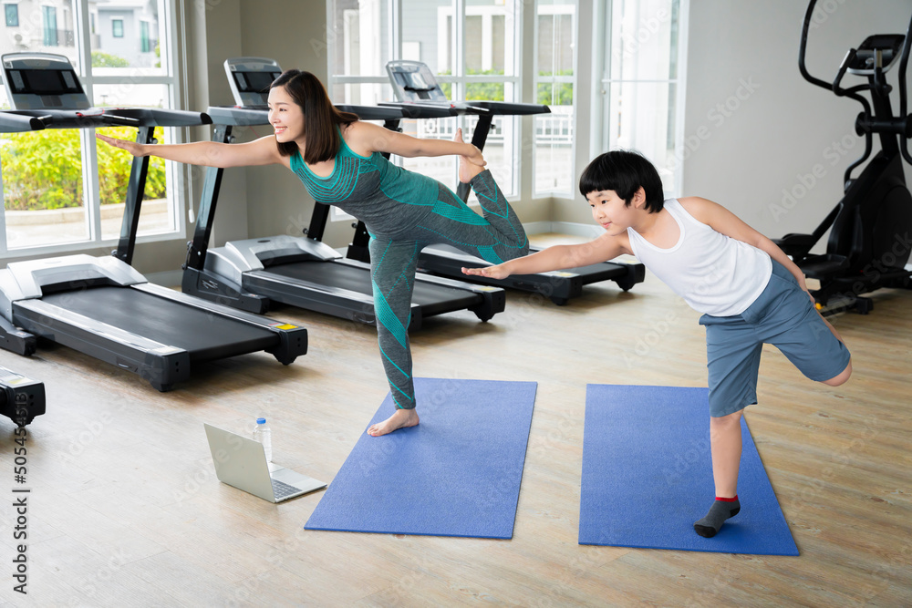 Mother doing yoga exercises with Asian son at village fitness. for her own health and being an example for her son to know how to take care of health through exercise a happy family Mother doing yoga exercises with Asian son at village fitness. for her own health and being an example for her son to know how to take care of health through exercise a happy family