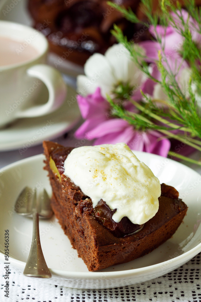 Chocolate plum cake with whipped cream, served with cocoa. Rustic style.