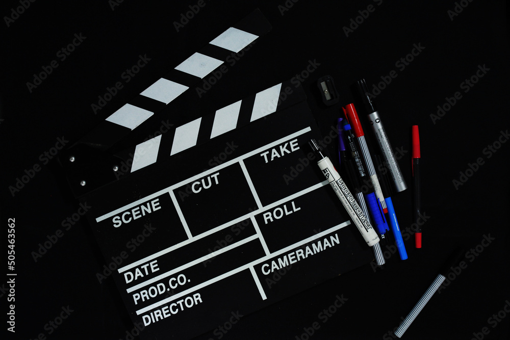 Clapperboard and stationery on black background
