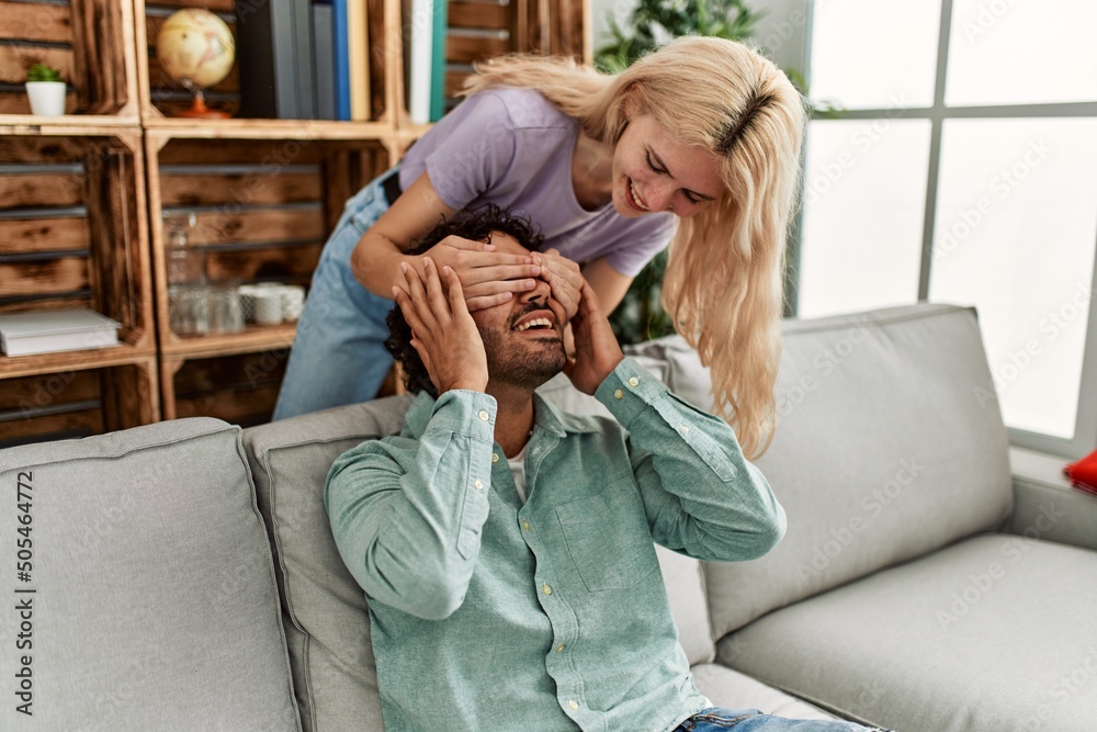 Fototapeta premium Woman surprising her boyfriend with hands on eyes at home.
