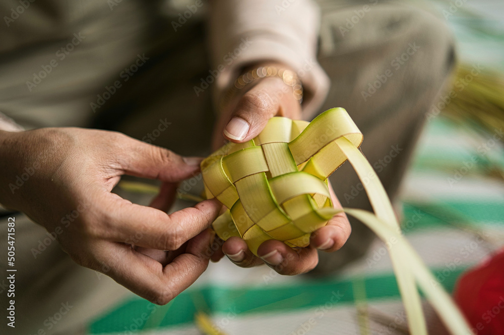 Φωτογραφία Closeup of a person's hands preparing Ketupat - a rice cake - by weaving the coc