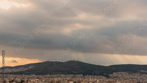 Sun beams and light rays with dramatic moody clouds above mountain near Athens, timelapse photo