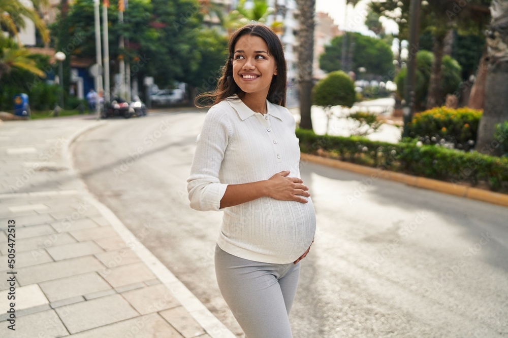 Young latin woman pregnant smiling confident touching belly at street Young latin woman pregnant smiling confident touching belly at street
