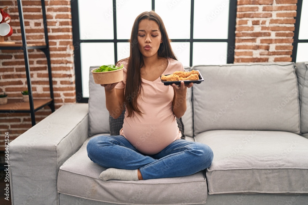 Φωτογραφία Young pregnant woman craving for food at home making fish face with mouth and squinting eyes, crazy and comical