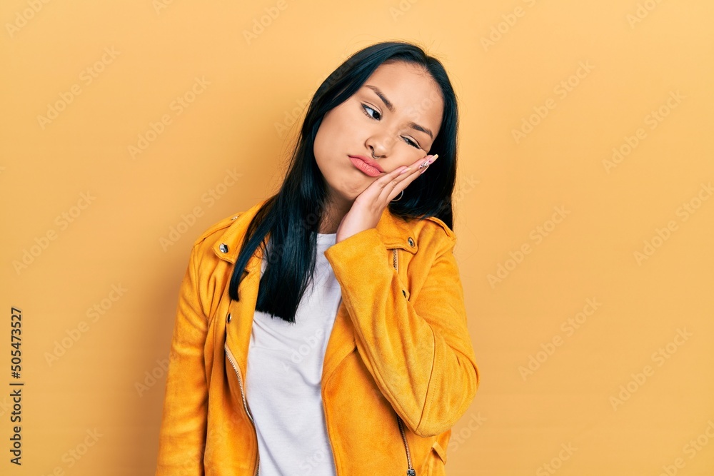 Beautiful hispanic woman with nose piercing wearing yellow leather jacket thinking looking tired and bored with depression problems with crossed arms. Beautiful hispanic woman with nose piercing wearing yellow leather jacket thinking looking tired and bored with depression problems with crossed arms.