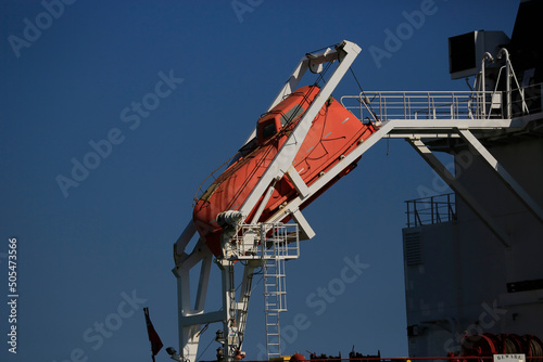 a lifeboat on a big ocean freighter is ready to be deplyed in a emergency