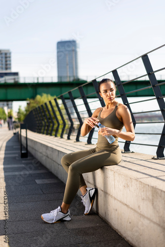 Young woman taking a break during exercise on the river promenade