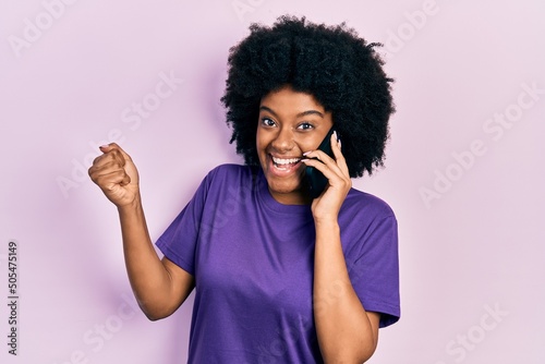 Young african american woman having conversation talking on the smartphone screaming proud  celebrating victory and success very excited with raised arm