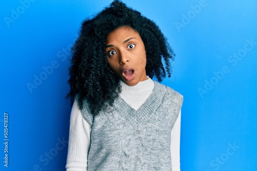 African american woman with afro hair wearing casual winter sweater in shock face  looking skeptical and sarcastic  surprised with open mouth