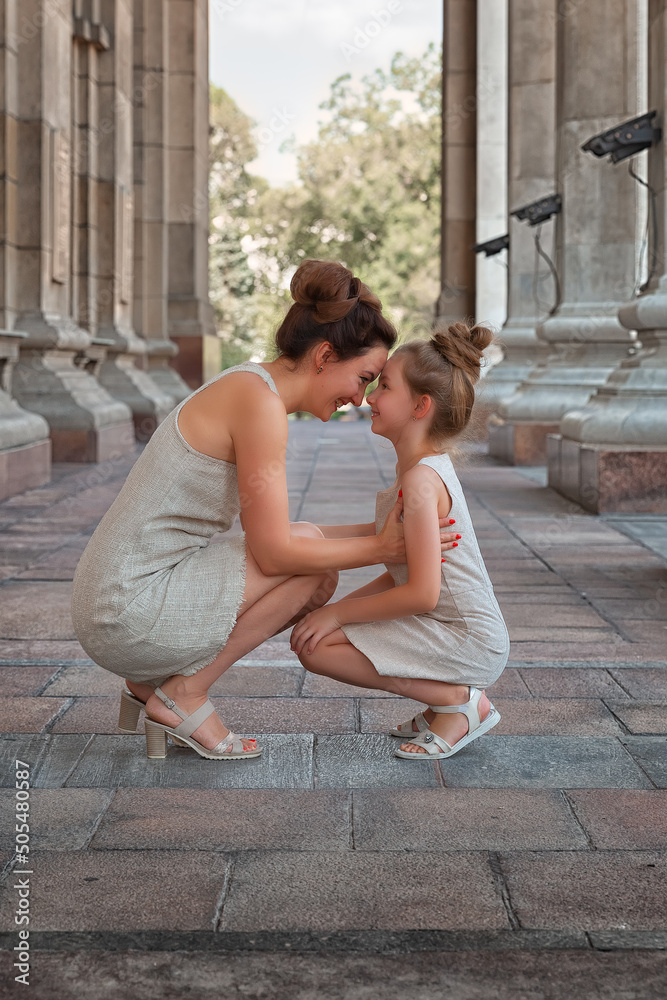 Happy smiling mom with a daughter child on a sunny summer day. Mother and girl kid walking around the city in the arch. Happy smiling mom with a daughter child on a sunny summer day. Mother and girl kid walking around the city in the arch.