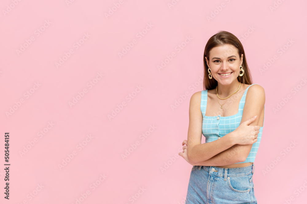 Attractive dark-haired girl in a bright summer outfit smiles with copy space. Positive smiling woman posing on pink background