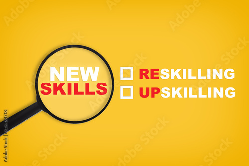 New skills written on yellow paper with magnifying glass. Development concept and reskilling and up skilling idea