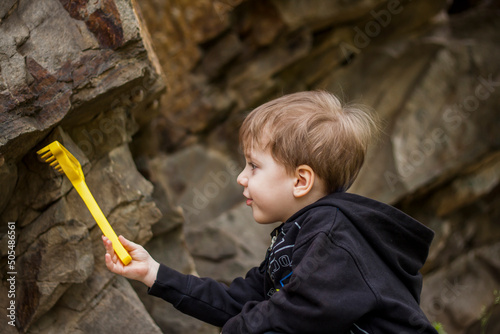 A boy-child on the background of a rocky mountain looks at something with curiosity and is surprised. Nature, rocks, mountains.