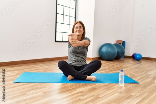Middle age caucasian woman smiling confident training yoga at sport center
