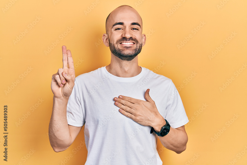 Φωτογραφία Young bald man wearing casual white t shirt smiling swearing with hand on chest