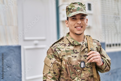Young arab man wearing camouflage army uniform outdoors looking positive and happy standing and smiling with a confident smile showing teeth