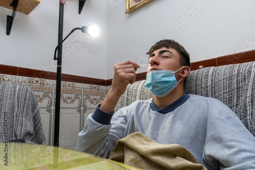 Sick Caucasian guy taking a Covid test while lying in bed at home photo