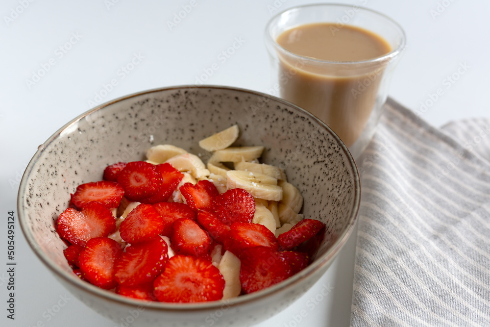 breakfast with sliced strawberries, bananas and curd in bowl and coffee with milk breakfast with sliced strawberries, bananas and curd in bowl and coffee with milk