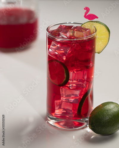 A tall glass of iced hibiscus tea with lime garnish
