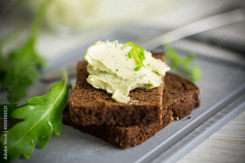 bread cheese spread with garlic and arugula on dark bread