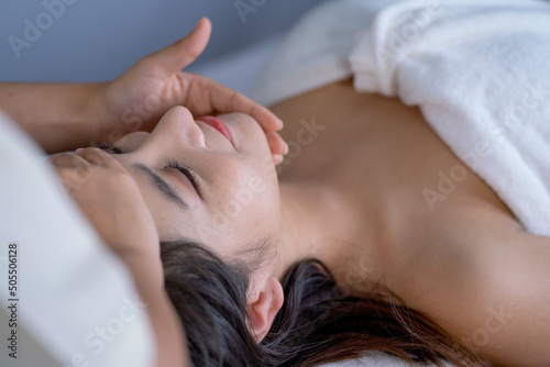 Close up face of beautiful Asian woman is treat with massage in spa room to get good health.