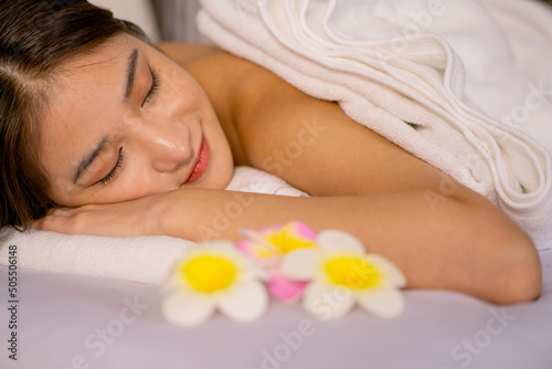 Close up beautiful Asian woman lie on bed and close her eyes with relax feeling during process of massage and spa for good health of woman.