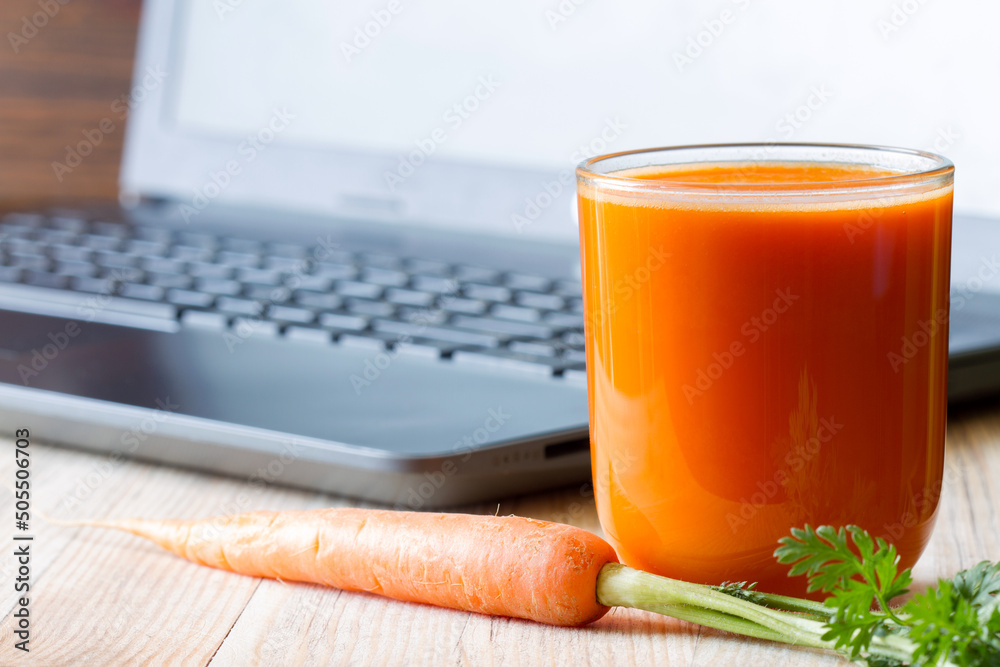 Carrot juice and laptop. Caring for eyesight while working with computer, concept - obrazy, fototapety, plakaty 
