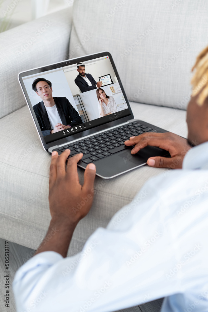 Video call. Global telecommuting. Wfh internet conference. Business man using laptop on couch working from home online with diverse team on screen. Video call. Global telecommuting. Wfh internet conference. Business man using laptop on couch working from home online with diverse team on screen.