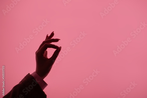 Back light silhouette of female hand in business suit showing ok sign on pink background. Signs and symbols, gesture and expression. Feminine blog template.