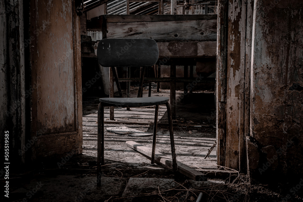 An old wooden chair in an abandoned greenhouse. Light and shadow. Shabby walls. Sad atmosphere. An old wooden chair in an abandoned greenhouse. Light and shadow. Shabby walls. Sad atmosphere.