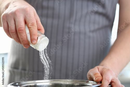 Professional cook hold saltcellar and add salt to soup, chef follow recipe, nutritious meal photo