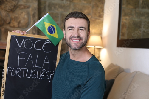 Portuguese teacher holding blackboard and Brazilian flag. TRANSLATION OF THE TEXT IN THE IMAGE: "Do you speak Portuguese?"