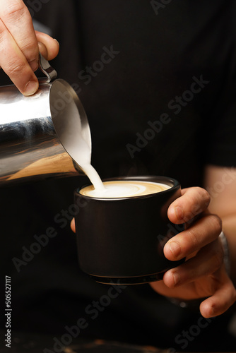 Barista pouring milk in coffee cup for make latte art