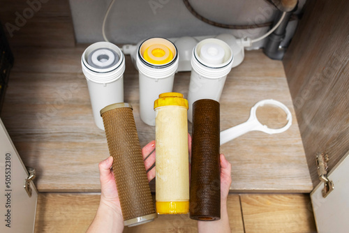 Plumber installs or change water filter. Replacement aqua filter. Repairman installing water filter cartridges in a kitchen. Clean water at home