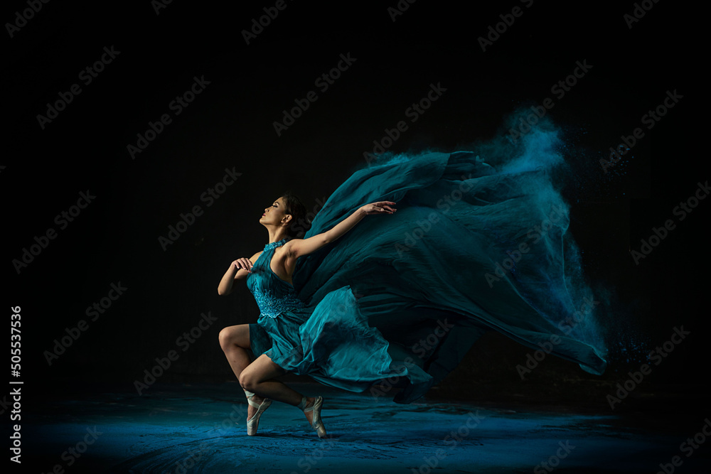 Emotional Southeast Asian ballet dancer in a green dress performing a move on a black background - obrazy, fototapety, plakaty 