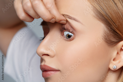 Close up woman holding her eyelid  suffering from eye disorder and disease. Foreign body sensation  itching and burning reddened eyes  irritation and discomfort. Check up at doctor and vision problems