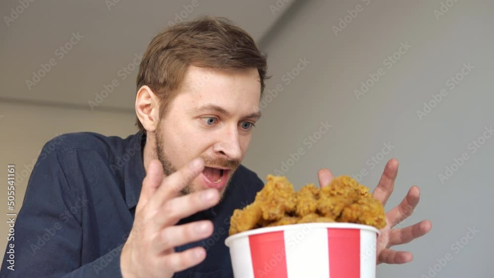 Hungry excited guy eating fried chicken. Caucasian man enjoying junk food. Hungry excited guy eating fried chicken. Caucasian man enjoying junk food.