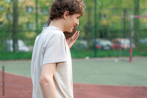 Cute young teenager in white t shirt with a ball plays basketball on court. Sports, hobby, active lifestyle for boys 