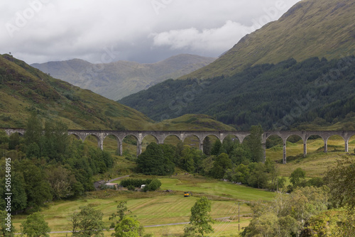 Aerial view of Glenfinnan Viaduct bridge surrounded by dense forest  and greenery fields in Scotland photo
