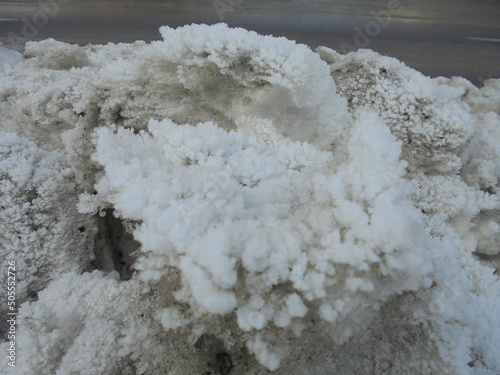 Massive heap of snow dirty from fumes piled up next to the road and covered by beautiful hoarfrost ice crystal structures resembling corals.