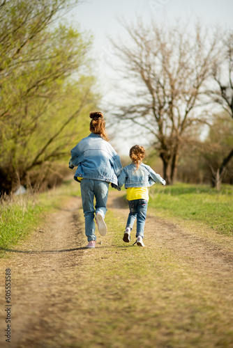 Two cute sister girls are running down an empty country road. Spring. Freedom. Childhood. Family.