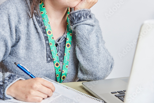 Woman studies or works using a sunflower lanyard, invisible disabilities symbol