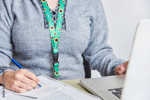 Woman studies or works using a sunflower lanyard, invisible disabilities symbol photo
