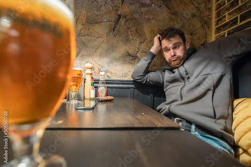 Totally drunk person at a bar looking towards a big glass of bee photo