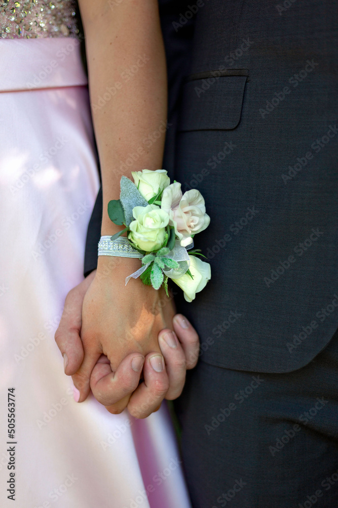 Φωτογραφία Closeup up shot of a couple holding hands with a wrist corsage at their prom wit