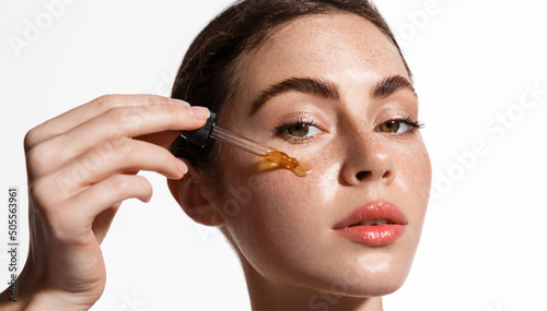 Photos Beauty woman with freckles, naked shoulders and nude face, apply serum vitamin c