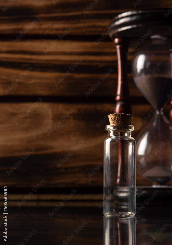 Small glass with empty cork cap, smoke, and more accessories, rustic wooden background, selective focus.